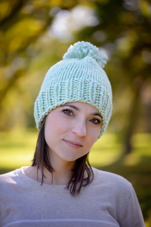 A young woman wearing our Snowball Fight Hat in the woods. Shown in Cucumber.