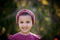 A little girl wearing our Little Twist Headband looks towards the camera. Shown in Archangel.